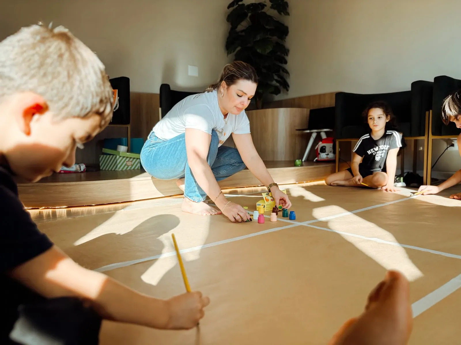 Terapeuta organizando materiais de pintura para atividade em grupo no Contato Espaço Terapêutico